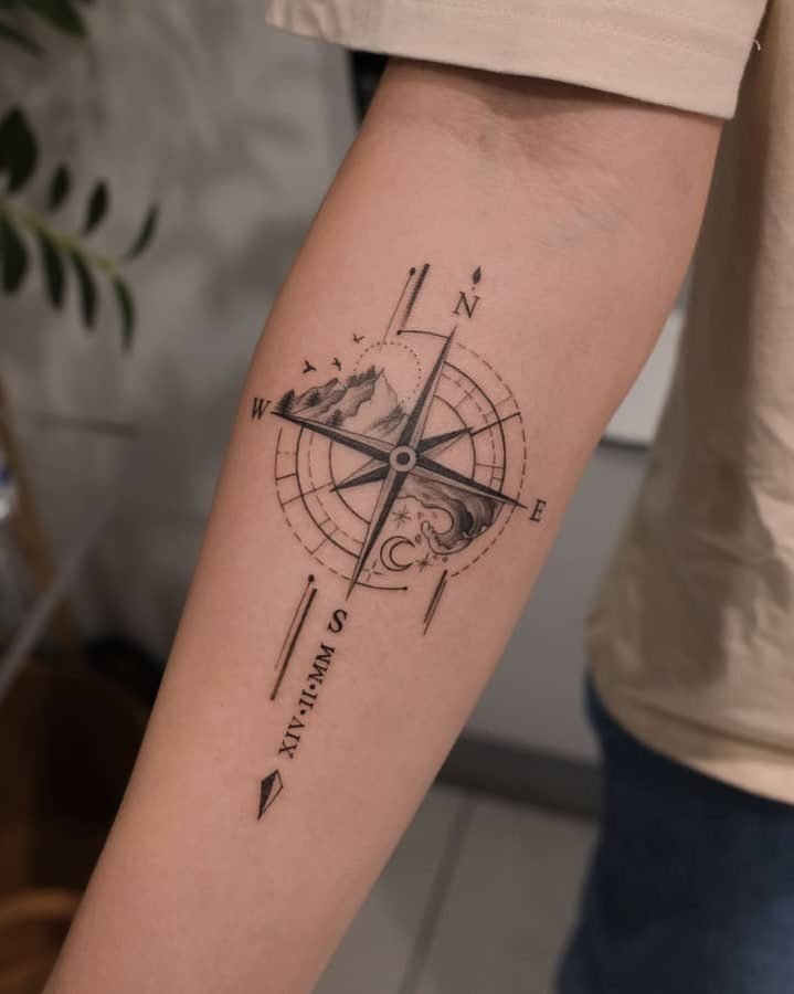 Mountain, moon, and wave compass tattoo on forearm