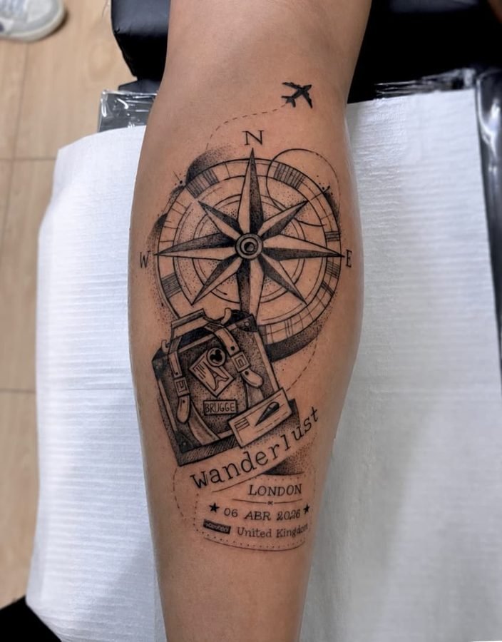Wanderlust luggage and compass tattoo on calf