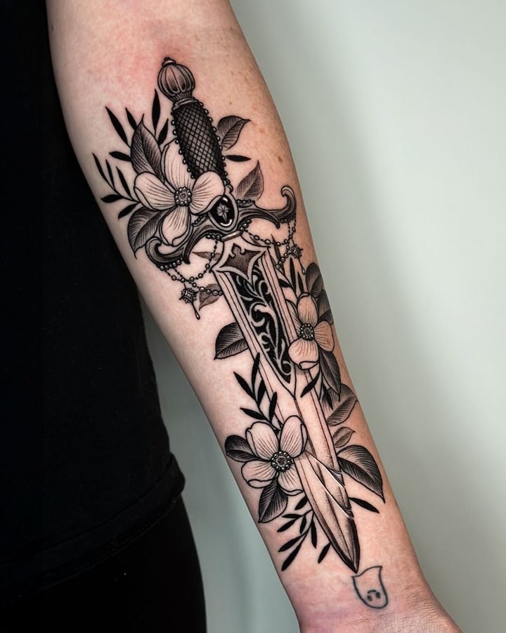 Ornate rose and dagger tattoo on forearm