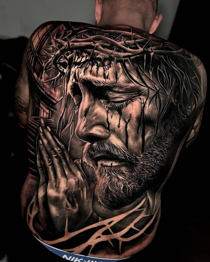 Full back tattoo of a religious portrait of Christ wearing a crown of thorns