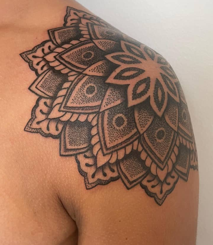Dotwork geometric mandala tattoo covering the shoulder cap, freehand-fit to the curve of the shoulder