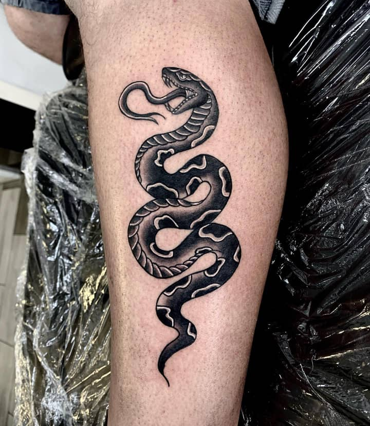 Bold traditional flash snake tattoo with heavy black fill and coiled body on the calf